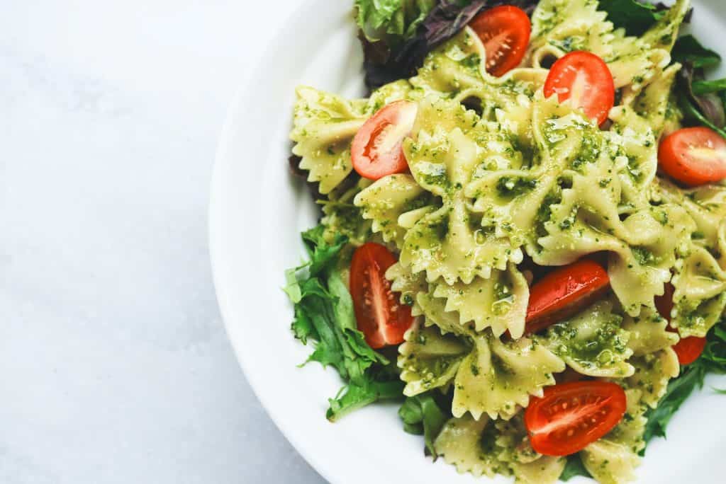 Pesto Pasta with Sliced Tomatoes Served on White Ceramic Plate