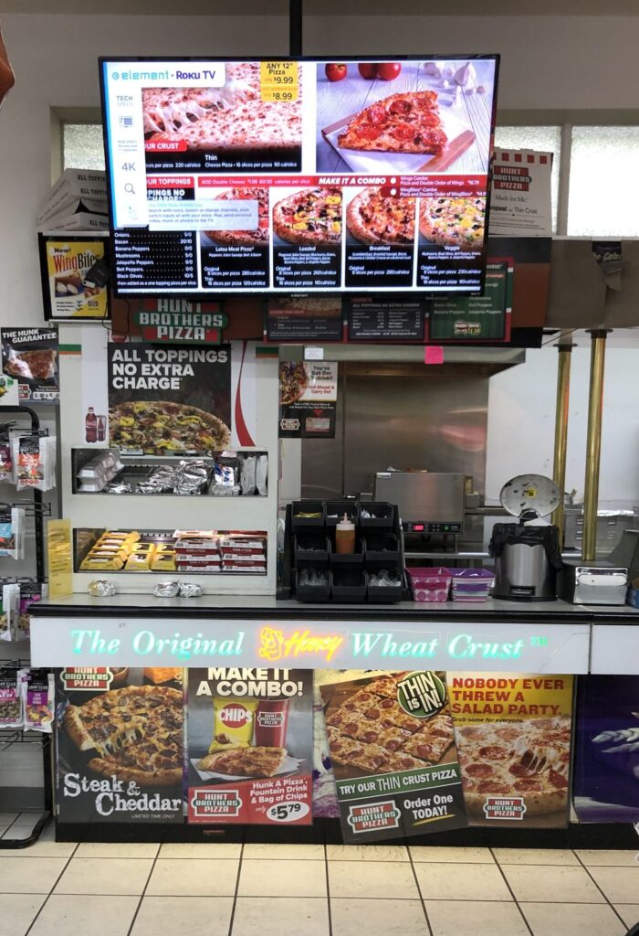 Hunt Brothers Pizza vegetarian options sign outside a convenience store