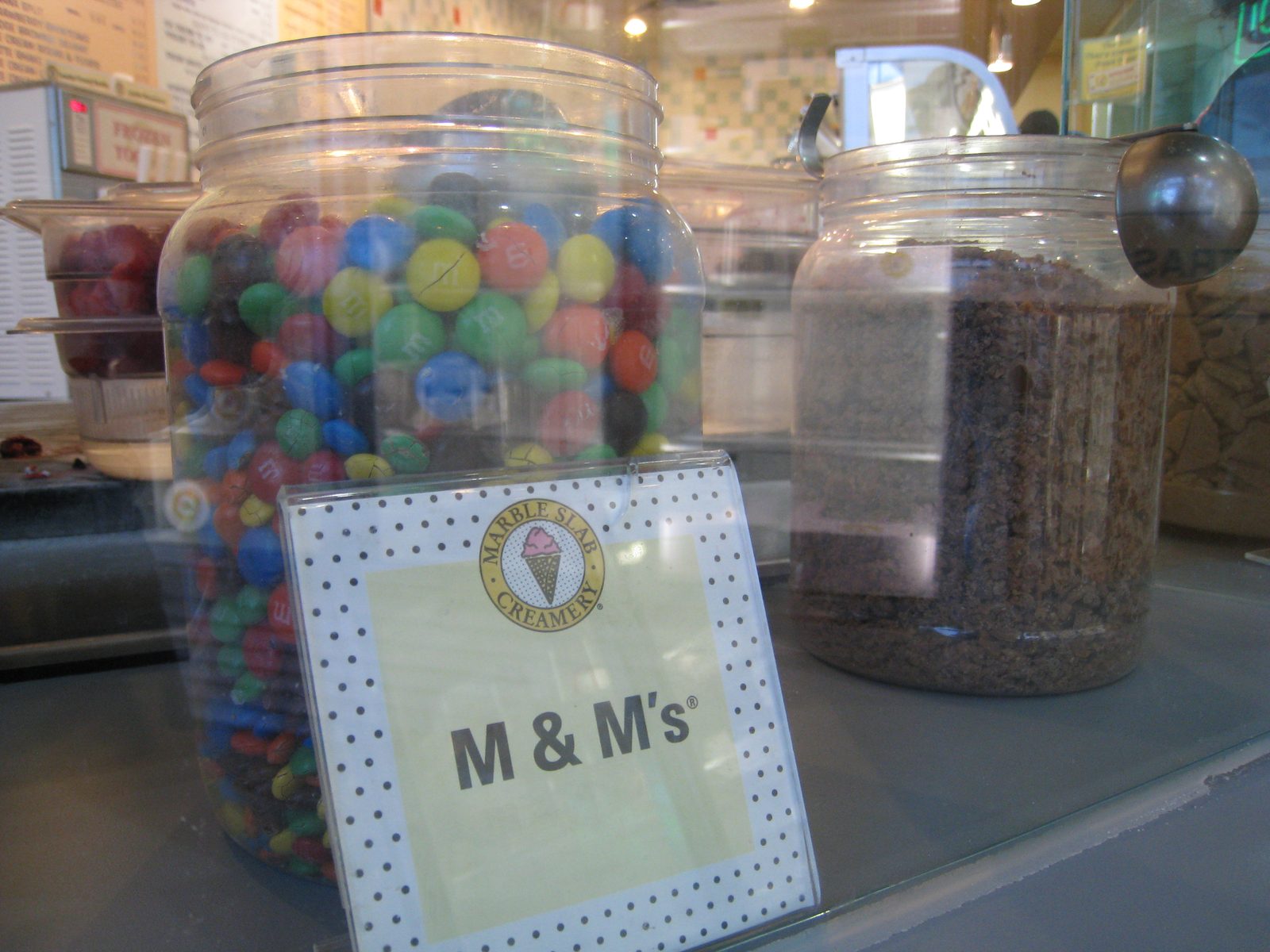 Marble slab creamery vegetarian options mix-in jars of M and Ms candy behind the counter